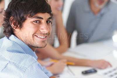 Buy stock photo A handsome young man sitting with his colleagues in the office boardroom