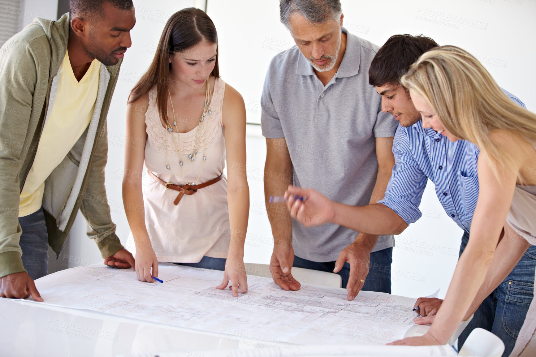 Buy stock photo A team of architects brainstorming in the boardroom over a set of blueprints
