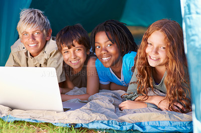 Buy stock photo Children, portrait and happy with laptop for camping in tent, social media or online movie with diversity in nature. Friends, face and group with smile outdoor on grass for trip, relax or holiday fun