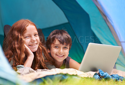 Buy stock photo Children, portrait and smile with laptop in tent for camping, social media or online movie with diversity in nature. Family, face and siblings or happy outdoor on grass for trip, relax or holiday fun