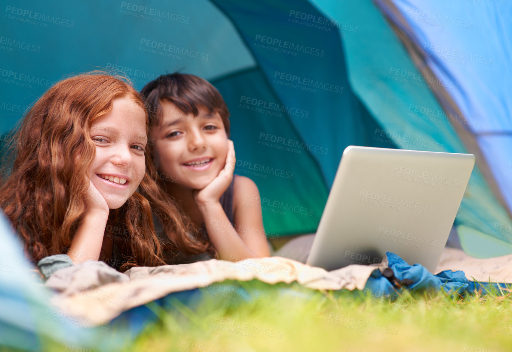 Buy stock photo Kids, portrait and happy with laptop in tent for camping, social media or online movie with diversity in nature. Family, face and siblings or smile outdoor on grass for trip, relax or holiday fun