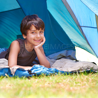 Buy stock photo Boy, child and camping, relax in tent and summer vacation with travel and happy in portrait outdoor. Rest on sleeping bag, young camper with smile and adventure in nature, childhood and recreation