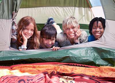 Buy stock photo Four friends lying in a tent together and smiling happily