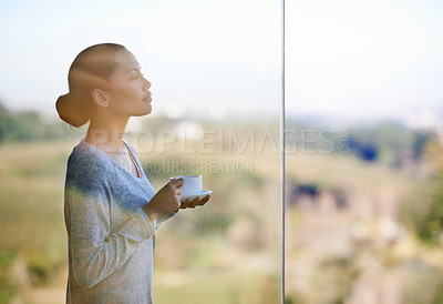 Buy stock photo Thorugh the window shot of a young woman drinking coffee while standing outdoors