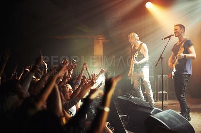 Buy stock photo Shot of a crowd of music fans reaching up at a guitarist on stage. This concert was created for the sole purpose of this photo shoot, featuring 300 models and 3 live bands. All people in this shoot are model released.