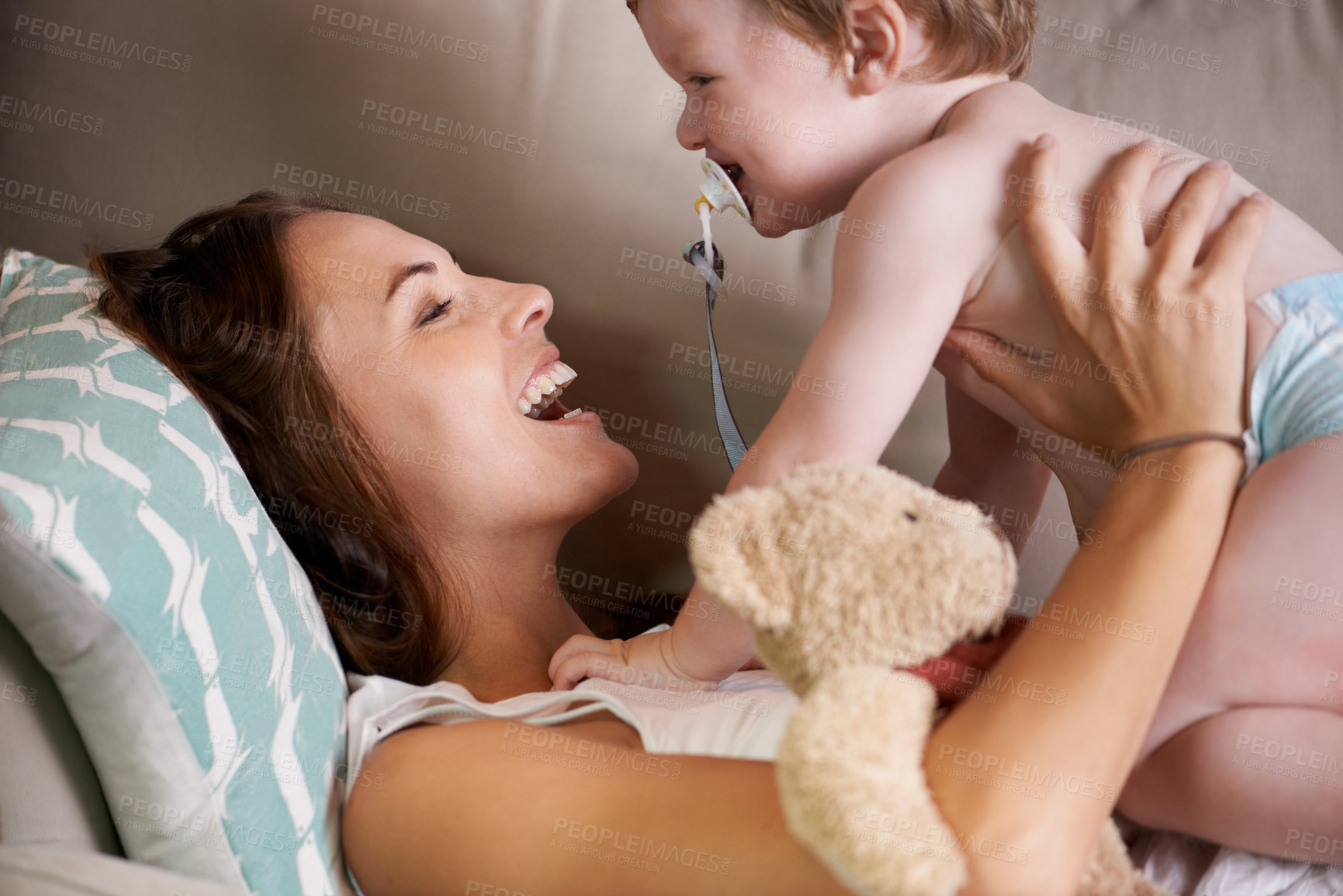 Buy stock photo A young mother lying on the sofa with her baby boy