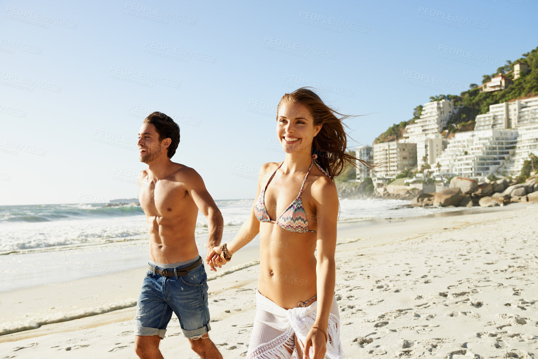 Buy stock photo Holding hands, love and couple walking at a beach with smile, fun and bonding in nature together. Travel, fun and happy people at sea for summer, romance or anniversary vacation in South Africa