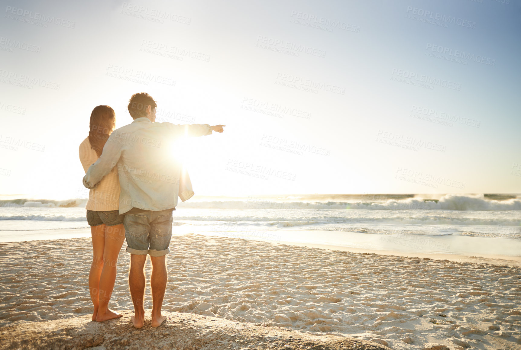 Buy stock photo Hand pointing, sunset beach and back of couple in nature with hug, support or love. Summer, romance and people at sunrise with ocean view, conversation or mockup on vacation, holiday or Florida trip