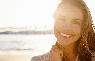 Buy stock photo A pretty young woman smiling confidently as the the sun sets on the beach in the background