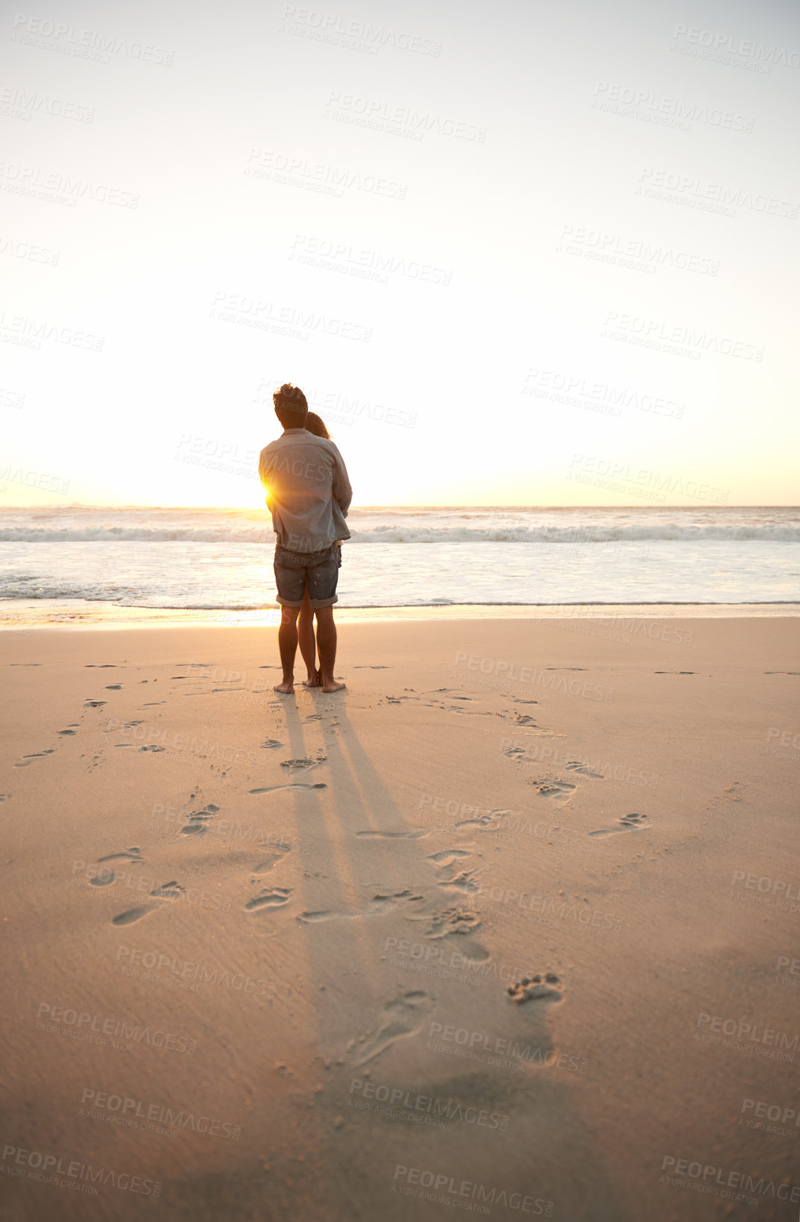 Buy stock photo Man, woman and beach love at sunset for romantic summer travel or adventure, bonding or marriage. Couple, footprints and embrace at water for dating tourism or nature vacation, environment or holiday