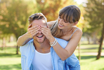 Buy stock photo A man giving his girlfriend a piggyback while she covers his eyes in the park