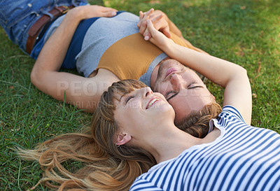 Buy stock photo Shot of a happy young couple lying in the park