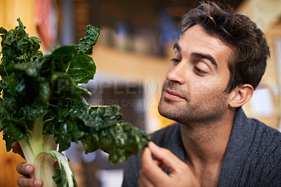Buy stock photo Shot of a young man choosing which spinach to buy
