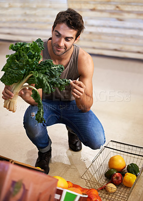 Buy stock photo Shot of a young man choosing which head of spinach to buy