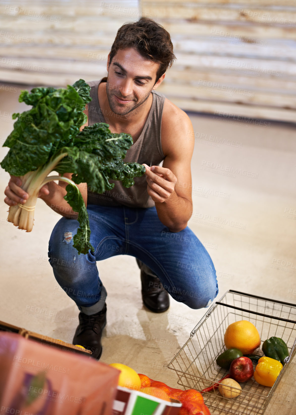 Buy stock photo Shot of a young man choosing which head of spinach to buy