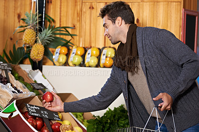 Buy stock photo Shot of a young man in a supermarket shopping for fresh produce