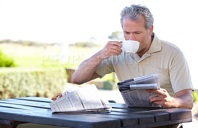Buy stock photo Relax, coffee and newspaper with man in park for lunch break, summer and calm. News, nature and morning with senior person in outdoors reading at picnic table for retirement, tea and crossword
