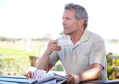 Buy stock photo Shot of a mature man drinking coffee while reading a newspaper