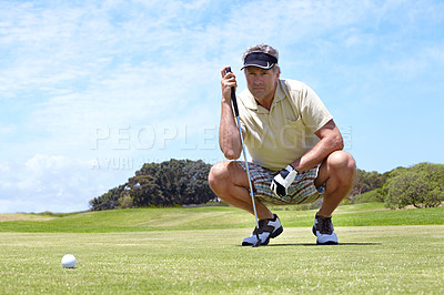 Buy stock photo A mature man lining up his putt on the green