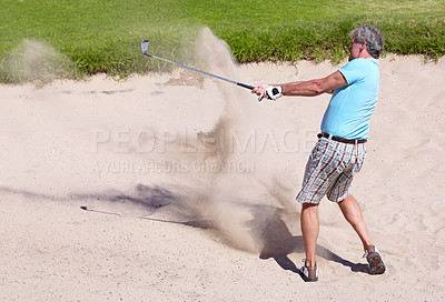 Buy stock photo Action shot of a mature man playing a shot from a sand bunker