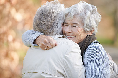 Buy stock photo Two senior ladies embracing with autumn shaded trees in the background
