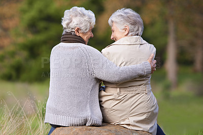 Buy stock photo Senior friends, hug and support by outdoor in nature, together and bonding on retirement on holiday. Elderly women, embrace or discussion on vacation in countryside, back or social with care on rock