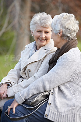 Buy stock photo Senior friends, love and talking by outdoor in nature, together and close bonding on retirement on holiday. Elderly women, smile or looking at face in countryside, happy or social with care on rock
