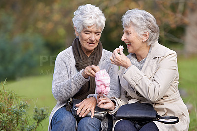 Buy stock photo Elderly women, eating and snack in park with candy floss, happy and together to relax on retirement outdoors. Senior friends, smile and junk food on vacation in countryside and bonding in nature