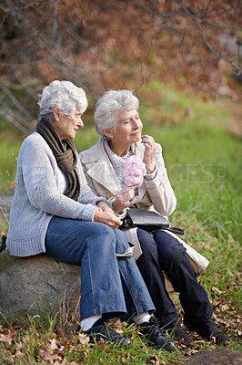 Buy stock photo Elderly women, hungry and snack in park with candy floss, happy and together to relax on retirement in outdoor. Senior friends, smile and junk food on vacation in countryside and bonding in nature