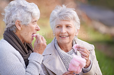 Buy stock photo Senior women, eating and snack in nature with candy floss, together and relax on retirement outdoor. Elderly friends, happy and junk food on vacation in countryside, bonding and social in park