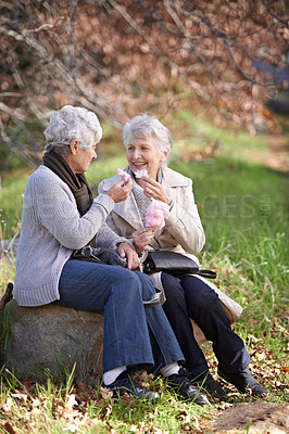 Buy stock photo Elderly women, happy and snack in park with candy floss, eating and together to relax on retirement in outdoor. Senior friends, smile and junk food on vacation in countryside and bonding in nature