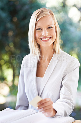 Buy stock photo Portrait of a happy young woman smiling at the camera while holding a business card