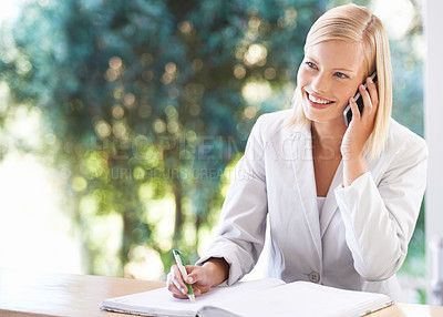 Buy stock photo Phone call, receptionist and woman taking notes at reception, writing and talking to contact. Smile, notebook and female clerk with cellphone for reservation, appointment and booking at hotel or spa.