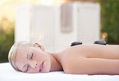 Buy stock photo Spa, woman and hot stone on massage bed with peace for wellness, zen and beauty treatment for body care. Person, relax and stress relief at resort, salon table and luxury on holiday or vacation