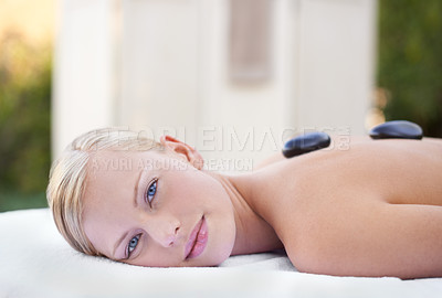 Buy stock photo Woman in portrait, hot stone massage in spa with wellness, healing and holistic treatment at luxury resort. Stress relief, zen and female person with rocks on back for self care and physical therapy