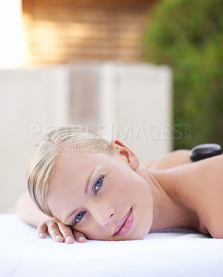 Buy stock photo Face of woman, hot stone massage at spa with healing and wellness, holistic treatment at luxury resort. Stress relief, zen and female person with rocks on back in portrait, self care and therapy