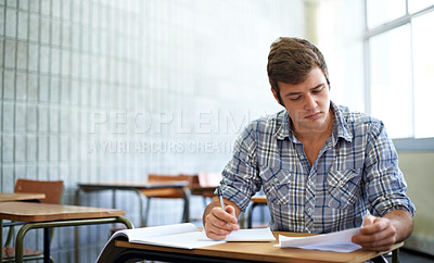 Buy stock photo Student, reading and learning in classroom for education, language development or knowledge in university. Young man writing notes and books for college research, essay paper or course information