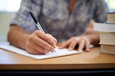 Buy stock photo A cropped shot of a young man making notes while studying