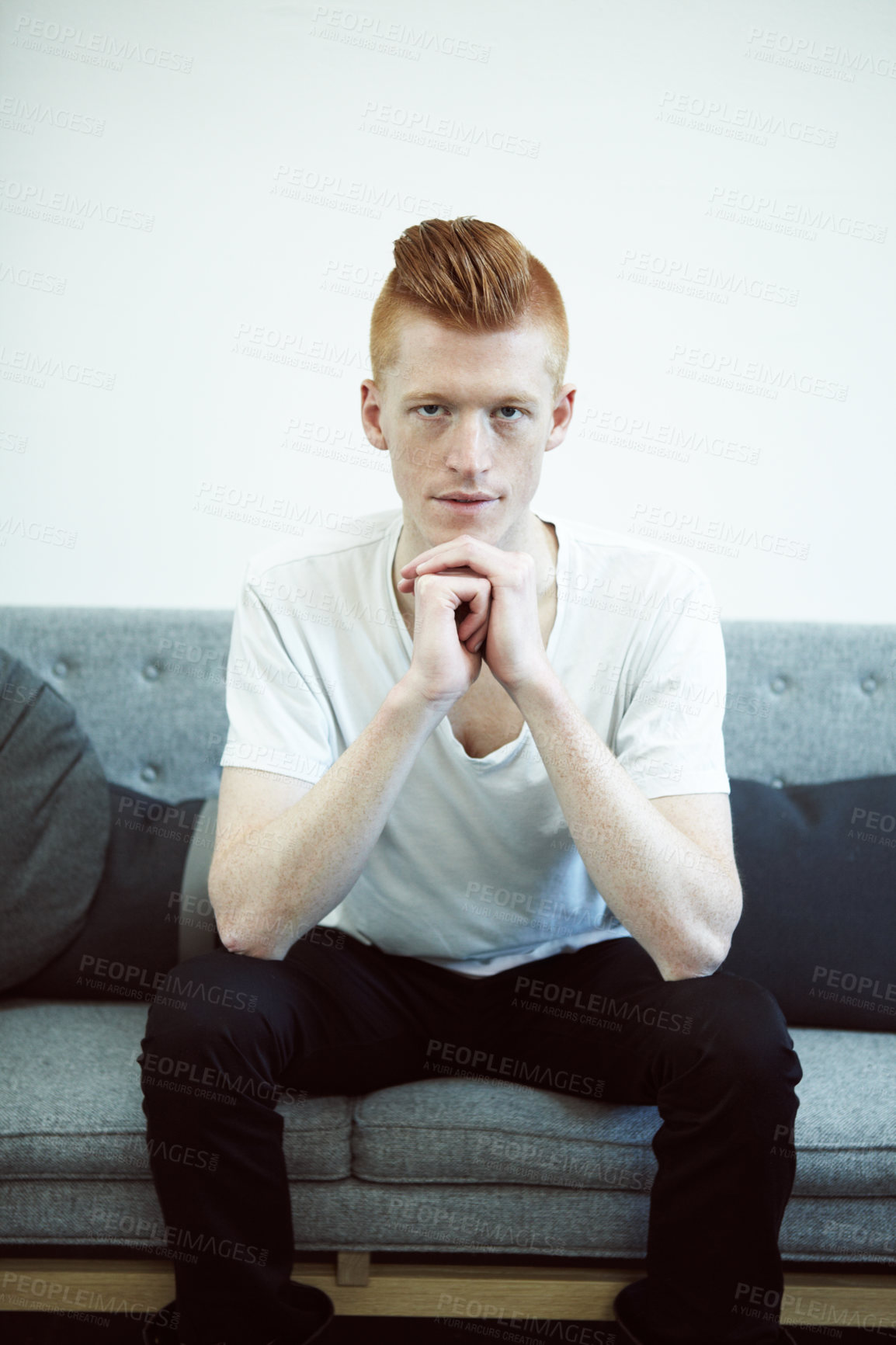 Buy stock photo Serious, couch and portrait of man with ginger hair or sit in a lounge in thought or for hipster fashion and against white wall. Sofa, think and young person with funky, casual style or relax at home