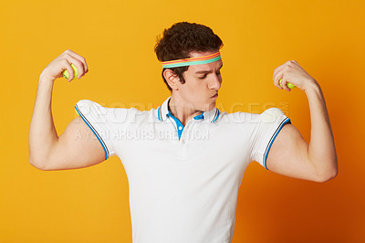 Buy stock photo Tennis, sports and man flexing arms with fitness and workout on yellow background. Person, model and athlete with wellness, goofy or funny with confidence and proud with health, strong or competitive