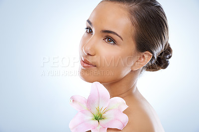 Buy stock photo Woman, face and flower in natural skincare, beauty or cosmetics on a blue studio background. Young female person smile with plant or petals on shoulder for glow, care or smooth skin on mockup space