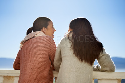 Buy stock photo Two young women standing outside on a balcony having a friendly conversation