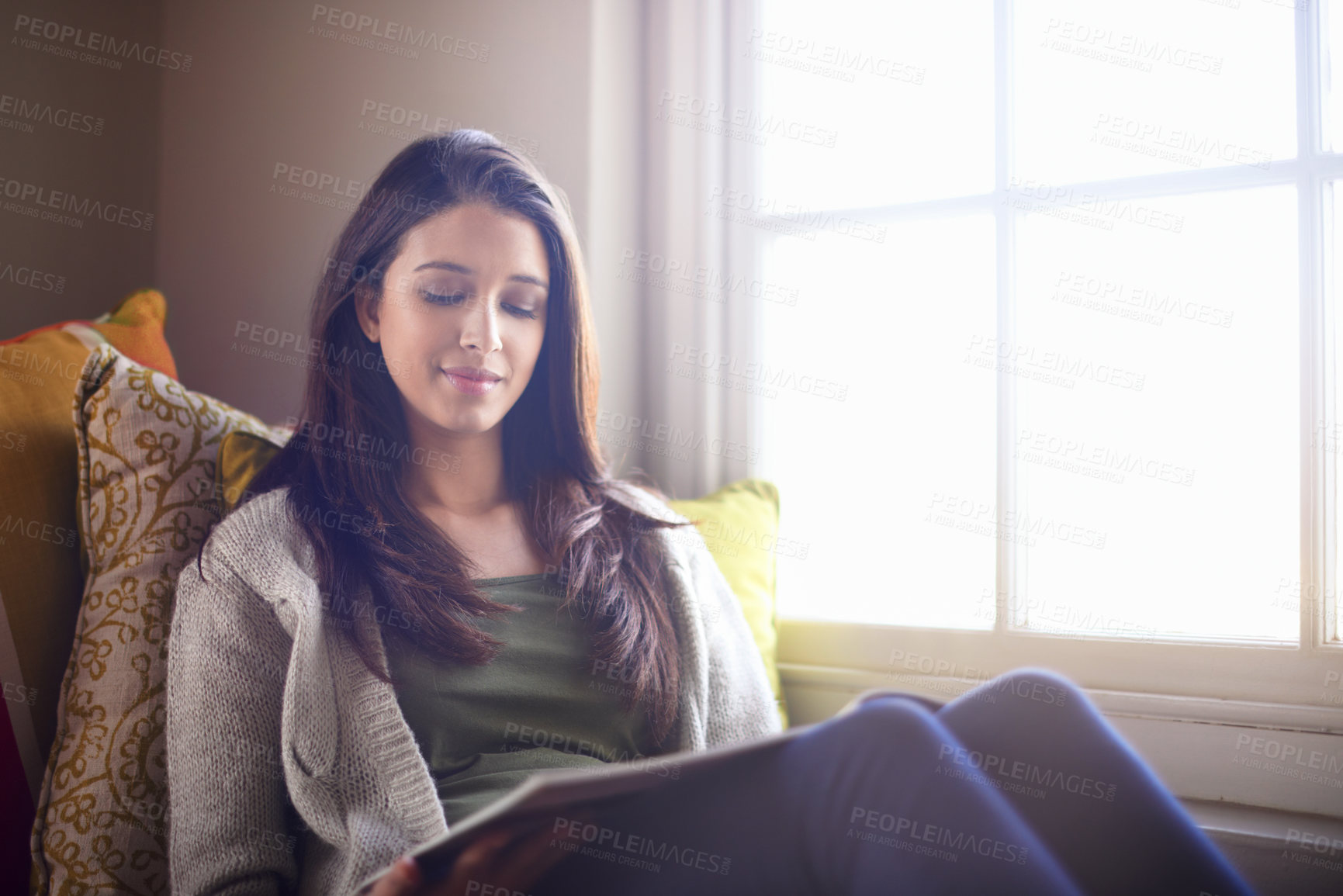 Buy stock photo A young woman reading a book at home