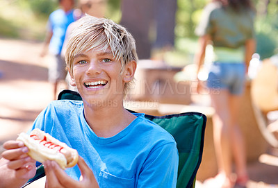 Buy stock photo Eating, hotdog and portrait of kid outdoor in camping chair and relax at barbecue with lunch. Happy, child and hungry for food from bbq in park, woods or forest on holiday or vacation in summer