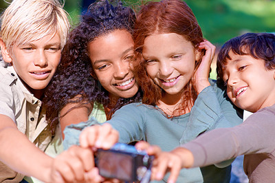 Buy stock photo A group of kids looking at a digital camera while sitting outside
