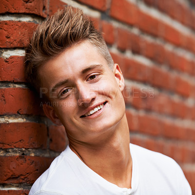 Buy stock photo Smile, portrait and young man on a brick wall in the city to relax and explore in Australia with pride. Happy, face and male person or student on an urban background with confidence while relaxing 