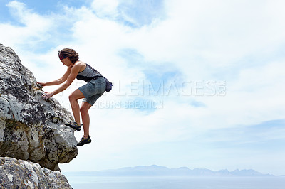 Buy stock photo A woman scaling a rockface on a sunny day