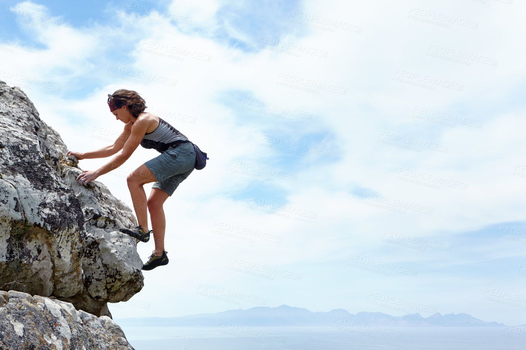 Buy stock photo A woman scaling a rockface on a sunny day