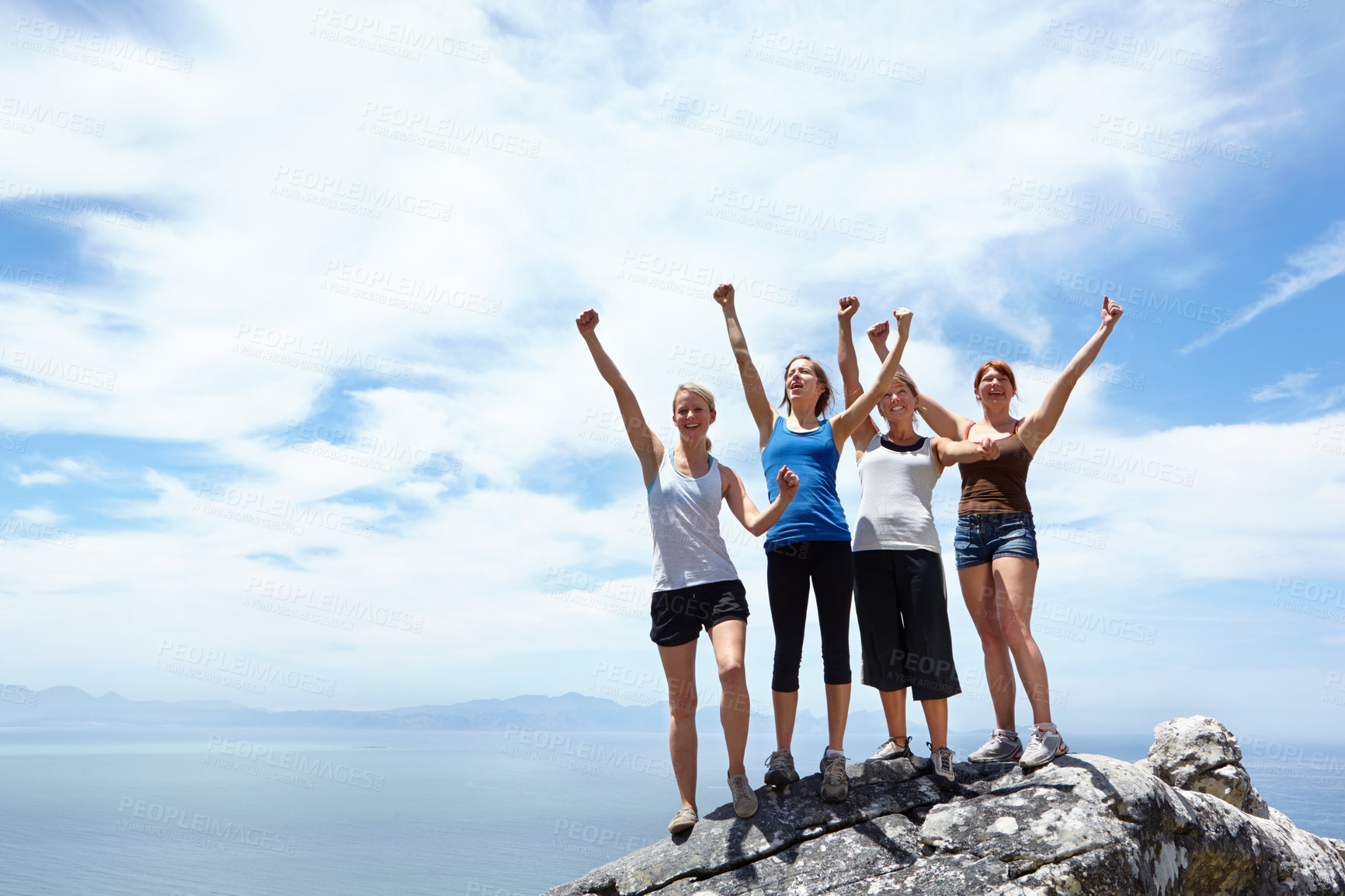 Buy stock photo Shot of a group of friends looking pleased after reaching the peak of a mountain