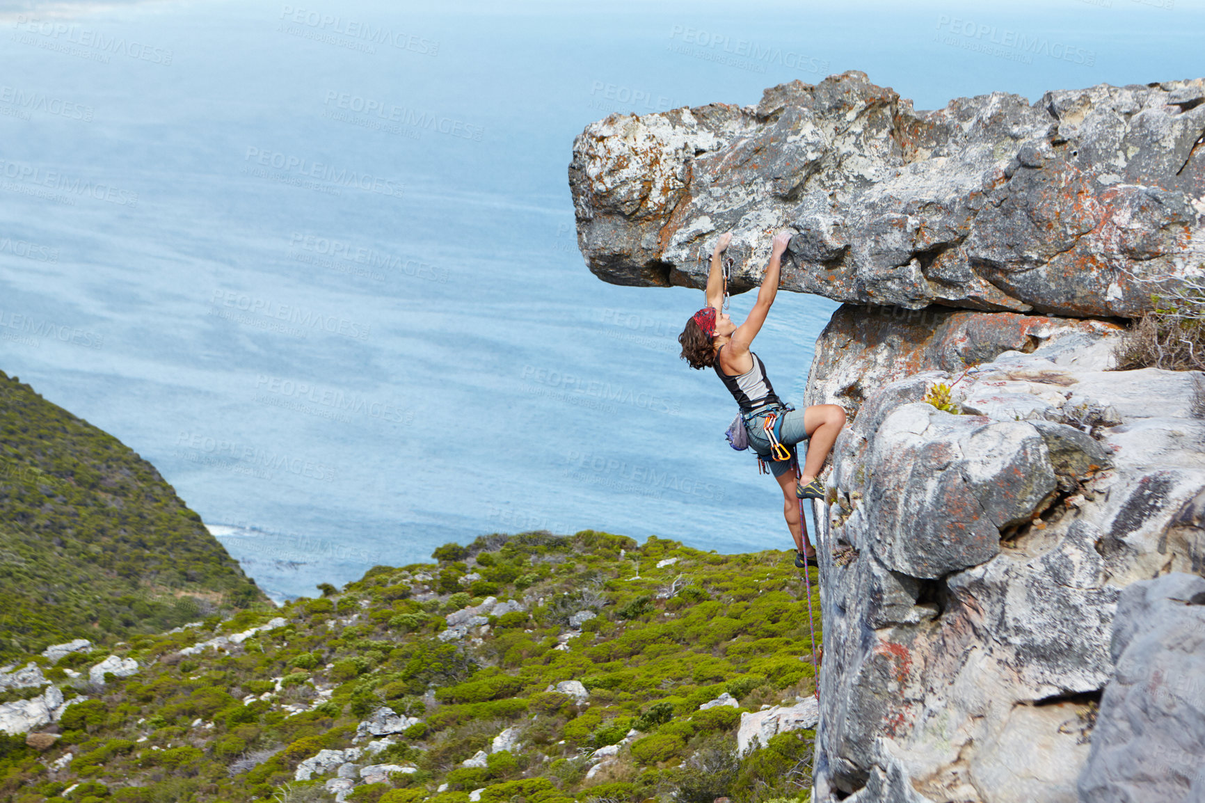 Buy stock photo A young woman rock climbing up the side of a mountain